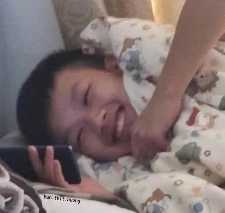 Meme nằm xem điện thoại cười khoái chí cực vui.