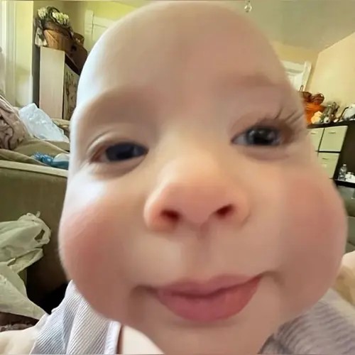 Hình chế vui em bé áp mặt sát ống kính trong phòng, đôi mắt tròn và môi chúm chím tạo góc chụp thần thánh