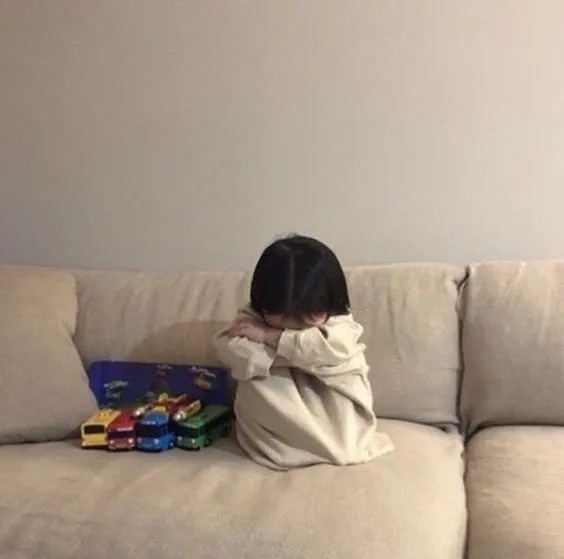 Bé ấm ức ngồi gục mặt vào đầu gối để khóc