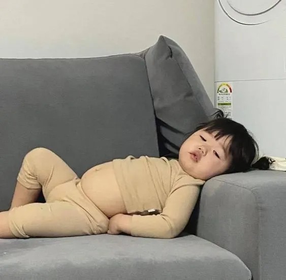 Cô bé nằm thoải mái trên ghế sofa với chiếc bụng tròn xoe